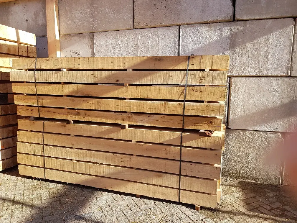 Stapel eiken balken van 150 mm tegen de gevel van de loods van CenWood